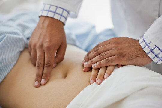 Doctor's hands examining a female patient's abdomen