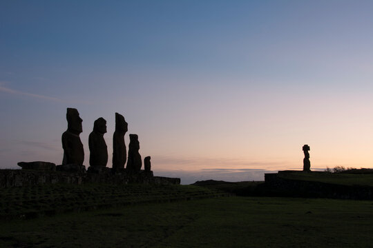 Six moais silhouetted against the early morning sky as the sun is about to rise; Easter Island, Chile