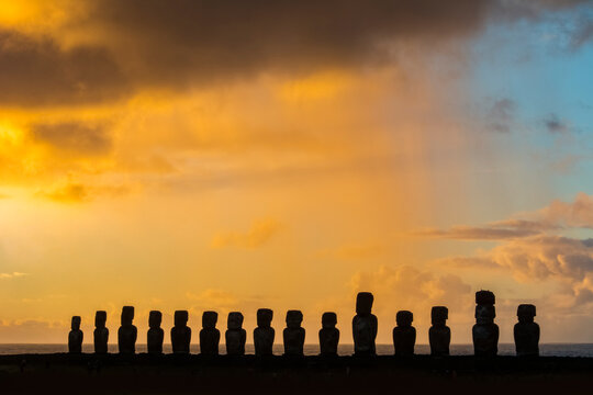 The fifteen moais of Tongariki silhouetted against the brightly coloured sky of sunrise; Easter Island, Chile