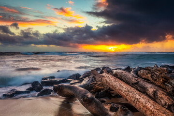 Sunrise over beach and ocean with a storm cloud and rain in the distance; Kauai, Hawaii, United States of America