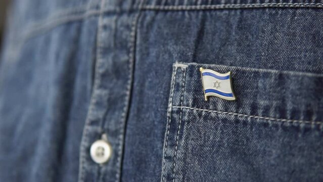 Metal badge with the flag of Israel is pinned on blue jeans jacket. Israel patriotism concept. Independence Day Holiday in Israel.