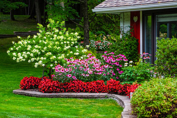Blossoming flowers decorating the yard of a house; Hudson, Quebec, Canada