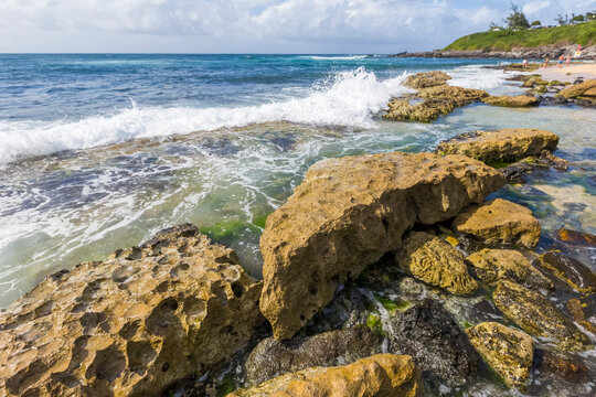 A beach view of Hookipa Beach with soft waves splashing over volcanic rocks; Paia, Maui, Hawaii, United States of America