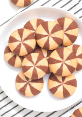 Plate with fresh delicious striped cookies on a striped napkin. Top view.