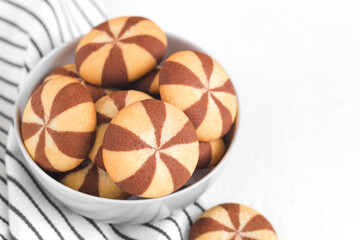 Striped vanilla chocolate cookies in a bowl on a white background. Copy space.