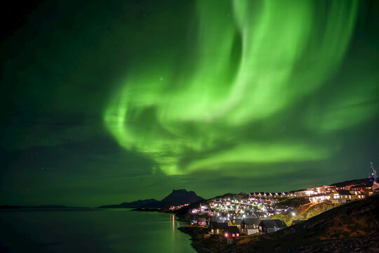Northern Lights over the glowing city of Nuuk; Nuuk, Sermersooq, Greenland