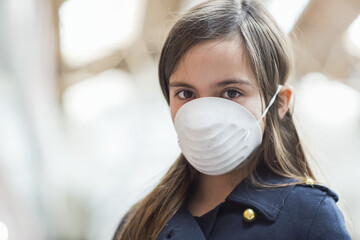 Young girl stands wearing a protective mask to protect against COVID-19 during the Coronavirus World Pandemic; Toronto, Ontario, Canada