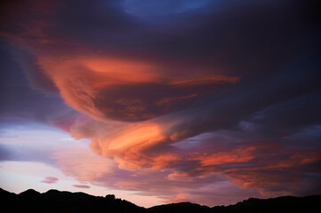 Sunrise with a sky loaded with beautiful clouds with blue and orange colors forming a swirl