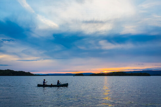 Man and woman paddling a canoe on Lough Derg lake at sunset; County Clare, Ireland