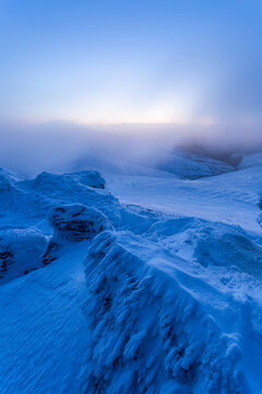 Snow-covered rocks in the Galty mountains in winter at dawn with low hanging clouds; County Tipperary, Ireland