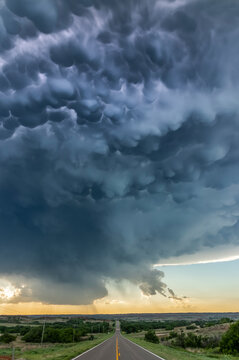 Mammatus from a collapsing severe thunderstorm is lit up by lightning as it crosses the highway; Durham, Oklahoma, United States of America