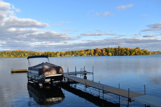 cloudy blue sky over a peaceful minnesota lake with dock and pontoon