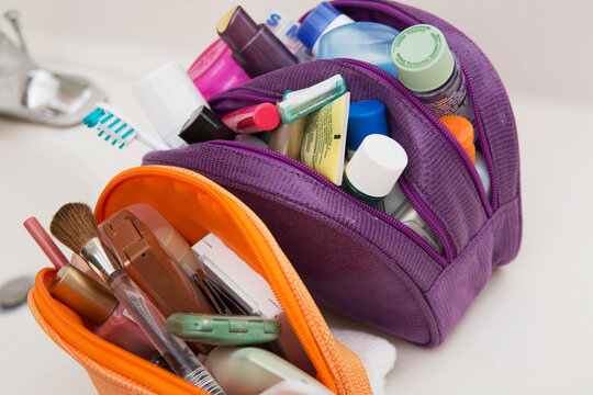 Women's toiletry and cosmetic travel bag on bathroom counter, filled with toothbrush, lotion, makeup and other beauty products, USA
