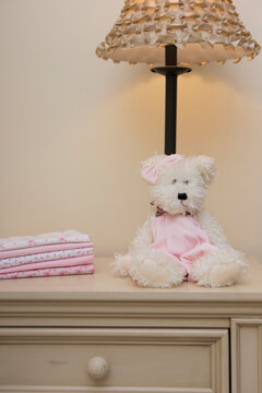Stack of Baby Blankets on Dresser next to Teddy Bear and Lamp in Nursery