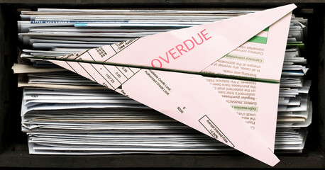 Stack of Unopened Bills with one Folded into Paper Airplane