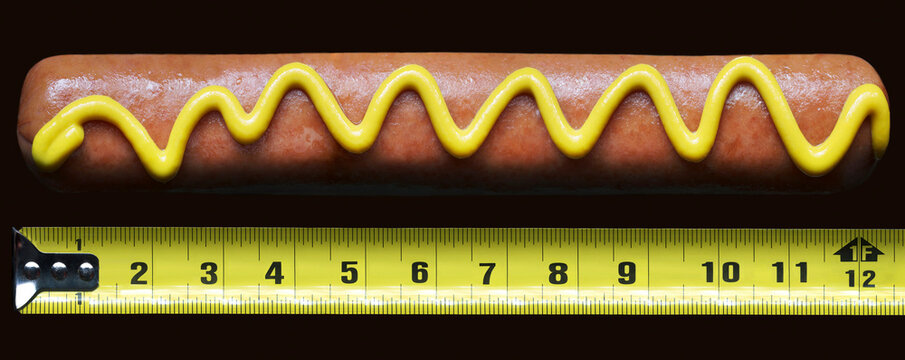 Hotdog with mustard beside measuring tape