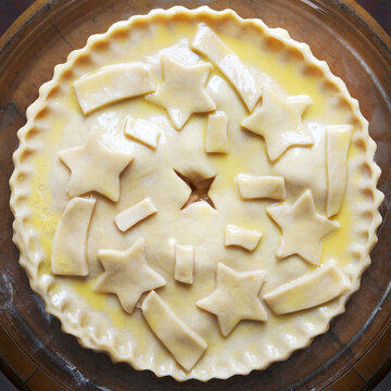 Overhead view of unbaked apple pie with star shaped cut-outs on top, studio shot