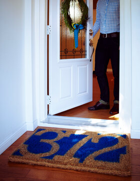 Man Opening Door to Home with Welcome Mat with House Number and Wreath on Door, Toronto, Ontario, Canada