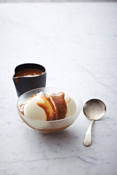 Vanilla Ice Cream with caramel sauce in bowl with spoon, studio shot