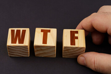 On a black surface, a man puts cubes with the inscription - WTF