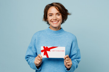 Young cheerful happy smiling woman in knitted sweater hold gift certificate coupon voucher card for...