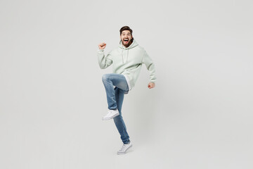 Fototapeta na wymiar Full body overjoyed excited young caucasian man wear mint hoody do winner gesture celebrate clenching fists say yes isolated on plain solid white background studio portrait People lifestyle concept