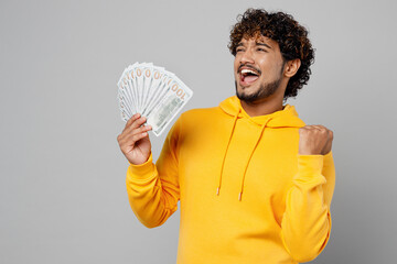 Young rich overjoyed wealthy smiling Indian man 20s he wear casual yellow hoody hold in hand fan of...