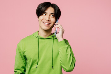 Young man of Asian ethnicity wear green hoody talk speak on mobile cell phone conducting pleasant...