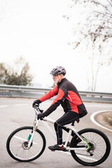older man riding a mountain bike on road, equipped and healthy