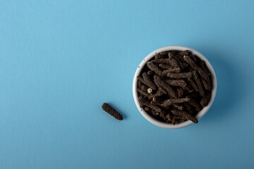 Dry Indian long pepper in white bowl. Piper Longum ,Piper retrofractum, Pippali, Long pepper. Herbal medicine. Top view.