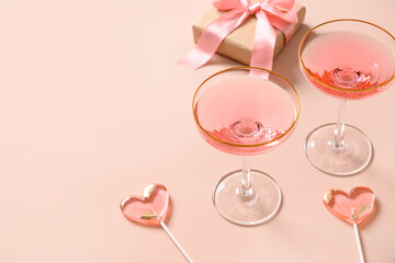 Festive champagne, romantic gift and two pink lollipops on stick on pink background. Valentine's day greeting card. Close up. Copy space.