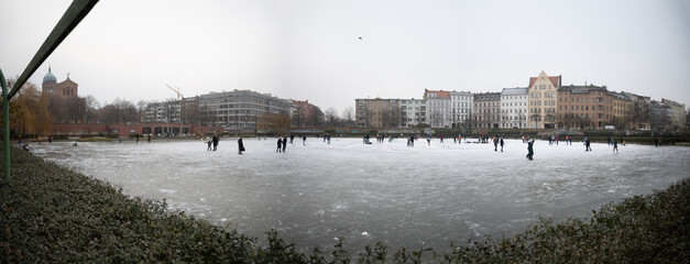 Fototapeta na wymiar Winter Skating on a pond in Lake Engelbecken Park in Berlin - Germany. People, ice-skating, daylight, winter, Panorama, Christmas.