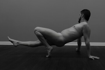 handsome nude male fitness model in artistic yoga pose in greyscale