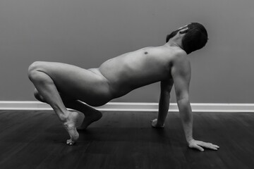 attractive nude male fitness model in unique yoga pose for artistic posing and modeling