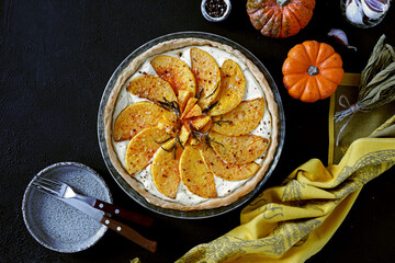 Pumpkin tart with cheese and spice on dark background, top view, copy space