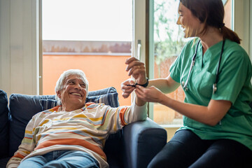 Home caregiver examining elder man, checking vitals by smart watch for health care diagnosis, nurse...