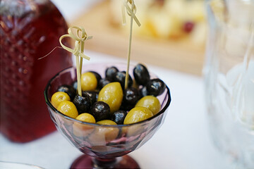 a bowl of green and black olives on the dining room table. 