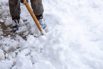 A man removes snow with a shovel on a winter day after a heavy snowfall.
