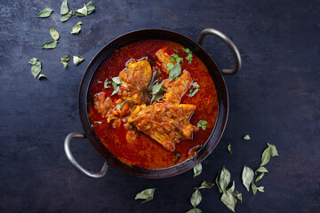 Traditional spicy Indian chicken Madras curry Rogan Josh with drumsticks and wings served as close-up in a korei bowl