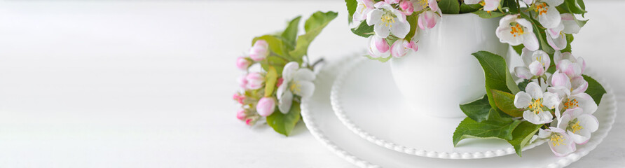 Beautiful table decor for a wedding dinner with a spring blooming apple tree flowers. Celebration of a special event. Fancy white plates, wineglasses. Banner copy space for text
