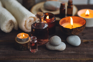 Obraz na płótnie Canvas Concept of natural essential organic oils, Bali spa, beauty treatment, relax time. Atmosphere of relaxation, pleasure. Candles, towels, dark wooden background. Alternative oriental medicine