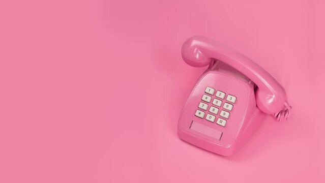 Pink push-button phone ringing stop motion on pink background With place for text on the left Horizontal frame