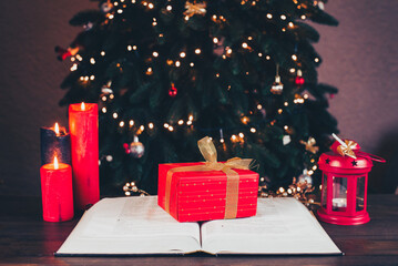 An open Bible on the table. Gift on the Bible. Prayer. Christmas background. Candles, lights and...