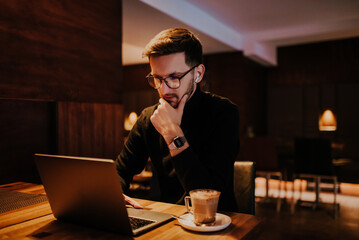 Young businessman using laptop for online meeting while sitting in modern cafe