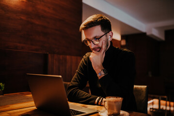 Young businessman using laptop for online meeting while sitting in modern cafe