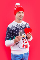 man in new year hat with champagne and heart. man hold champagne for new year eve in studio.