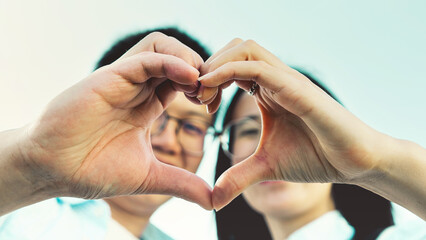 Couple make heart shape with hands- Portrait of young people making gesture love outdoors -Peace,Protection,healthcare and humanity bonding concept- Close up Asian friends outside at park