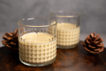 Close up of two glasses with eggnog, pine cones and space for text. Focus on the first glass.