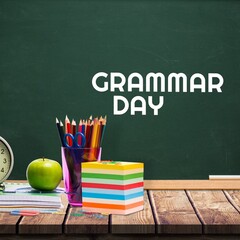 School equipment on wooden table against grammar day text on blackboard