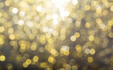 Abstract blurred glitter bokeh background in gold, on black